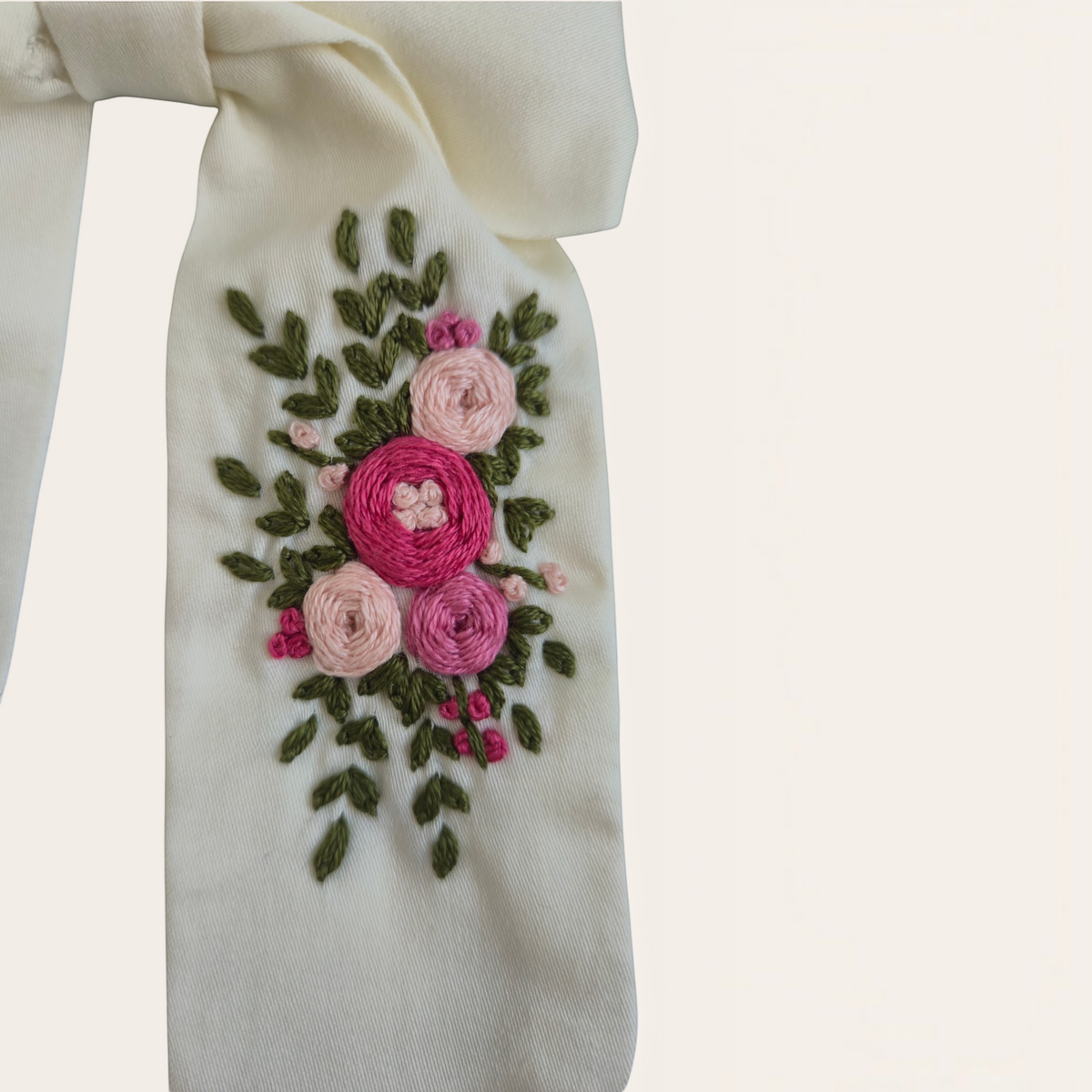 Grace Upon Grace ivory sailor bow featuring intricate hand-embroidered pink roses and green leaves on a hair clip.